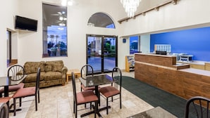 A hotel lobby with a reception desk, seating area, and large windows offering a view of the outdoors. - Days Inn by Wyndham Yuma (Yuma)