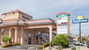 A Days Inn hotel with a sign indicating nearby amenities like The ARC Center, Oak Tree Inn, and Penny's Diner. - Days Inn by Wyndham Yuma (Yuma)