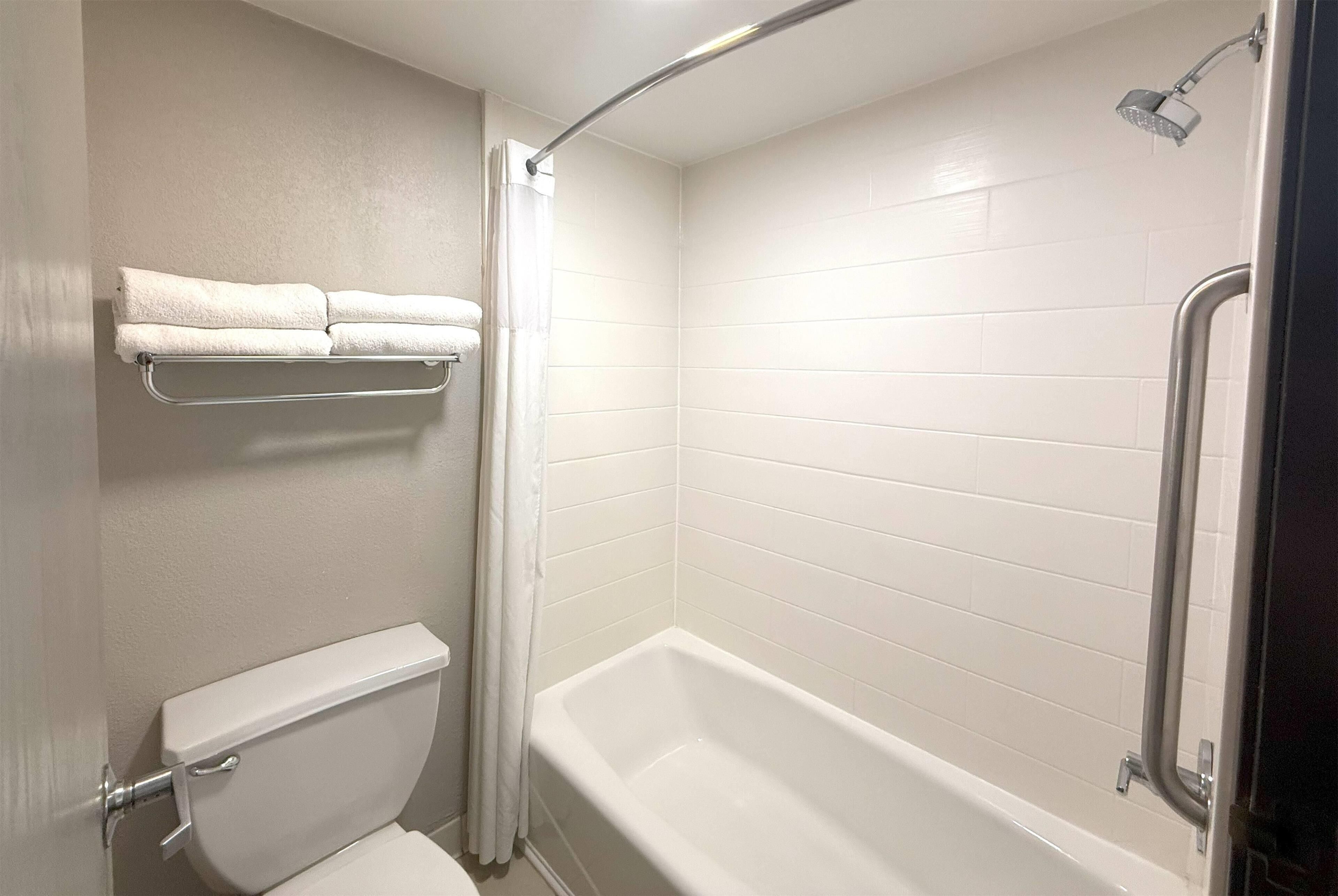 A bathroom with a white bathtub, a toilet, and a towel rack with two towels.