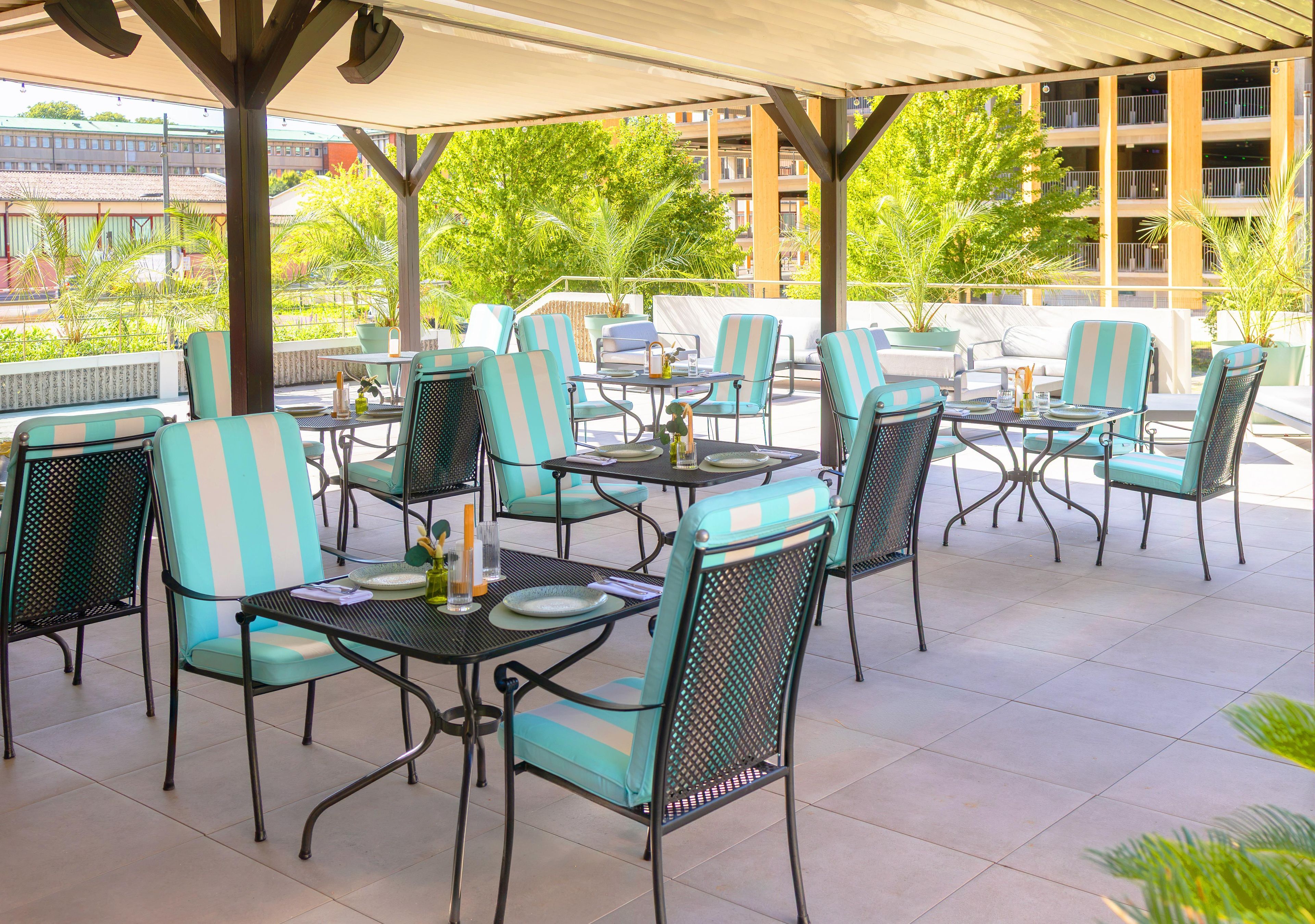 An outdoor patio area with multiple tables and chairs, some with cushions.