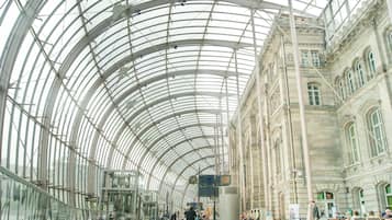 A spacious indoor area with a high, glass ceiling and classical architecture.