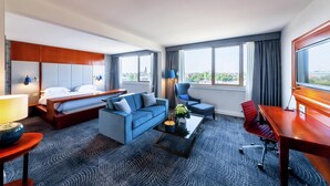 A hotel room with a bed, a sofa, a desk, and a chair.