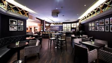 A restaurant interior with dark wood flooring, brick-patterned seating, and a bar area with a wine rack.