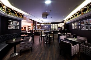 A restaurant interior with dark wood flooring, brick-patterned seating, and a bar area with a wine rack. - Hilton Strasbourg (Strasbourg)