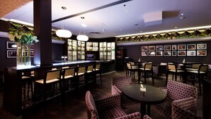 A bar area with seating, a bar counter, and a wall with framed pictures.