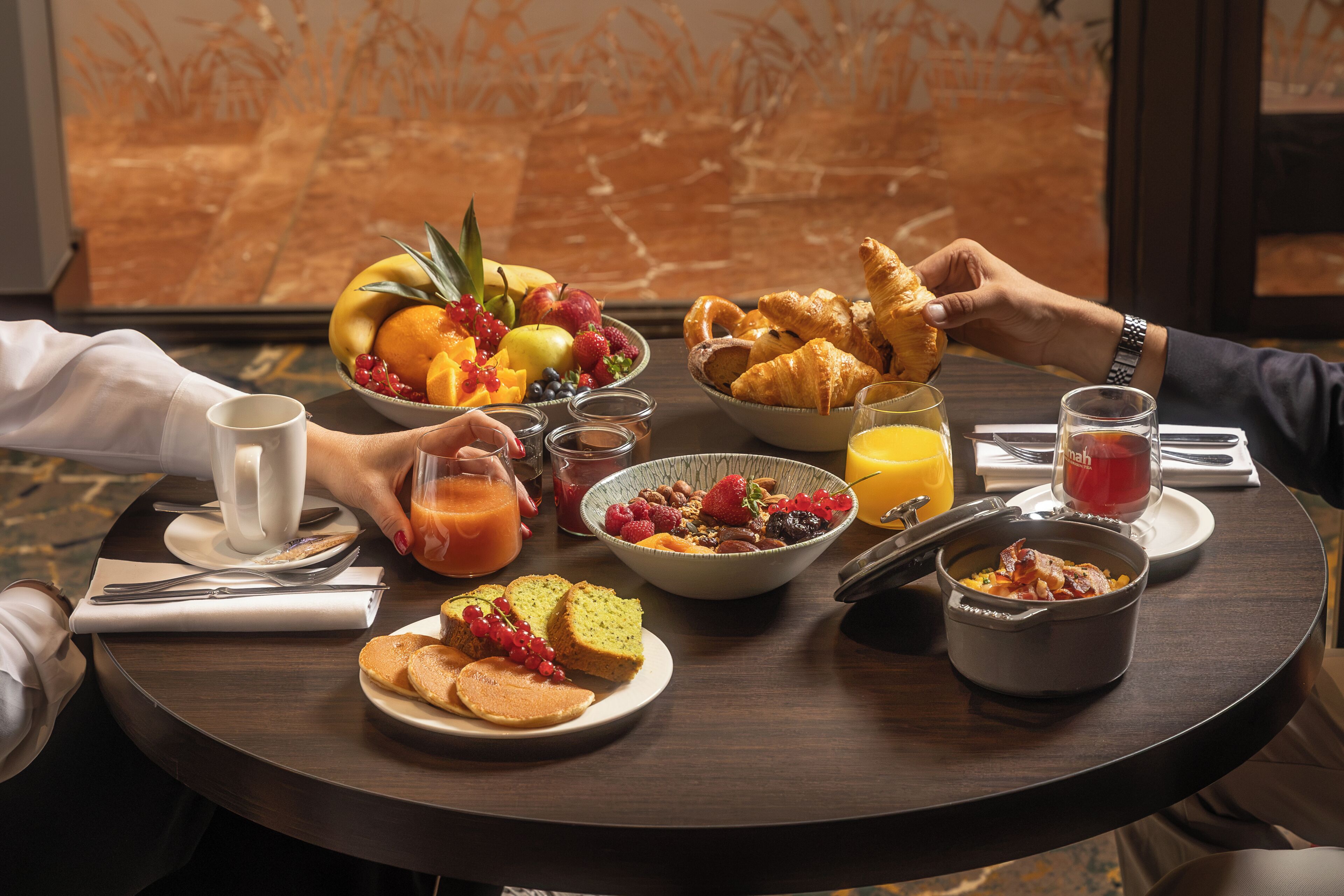 A breakfast setting with various food items and drinks on a round table.