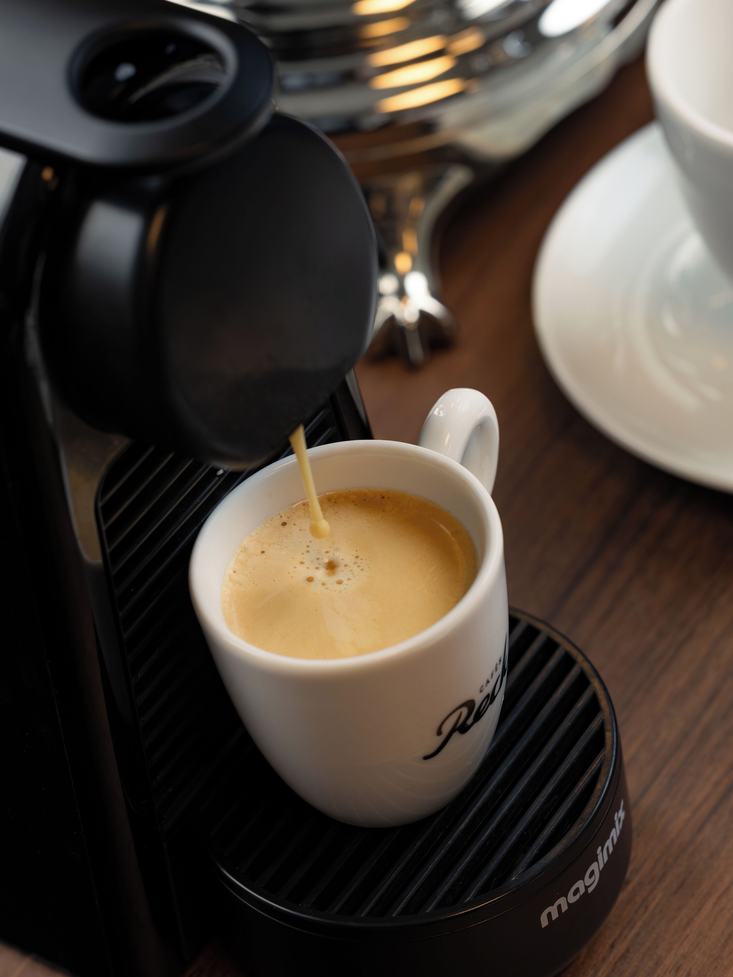Máquina de café servindo café numa chávena com apoio.