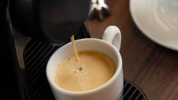 Máquina de café servindo café numa chávena com apoio.