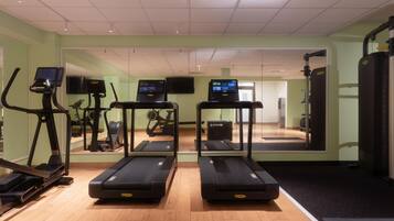 Ein Fitnessraum mit Laufbändern, Fahrrädern und Rudergeräten.