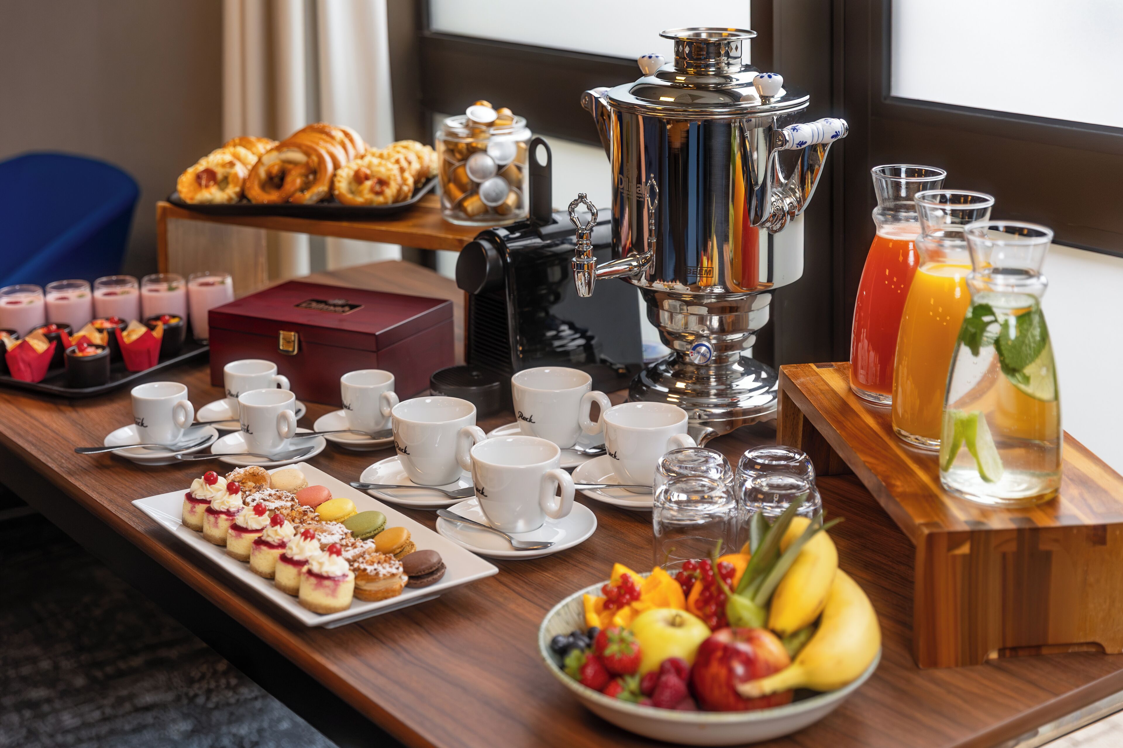 A breakfast buffet with pastries, a coffee machine, and a fruit bowl.