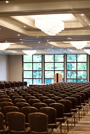 A conference room with rows of chairs, large windows, and a chandelier.