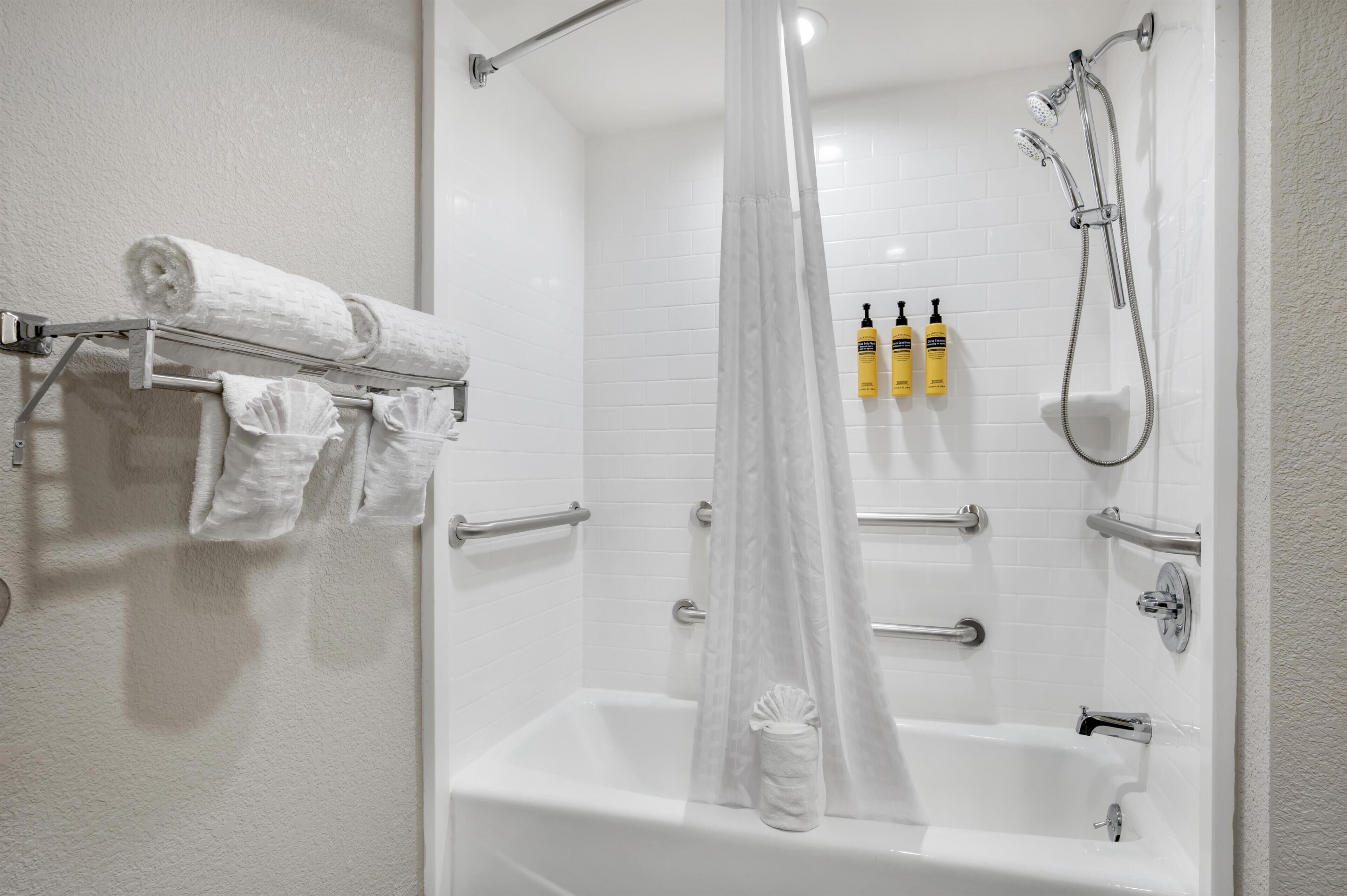 A white bathroom with a bathtub, shower, and towel rack.