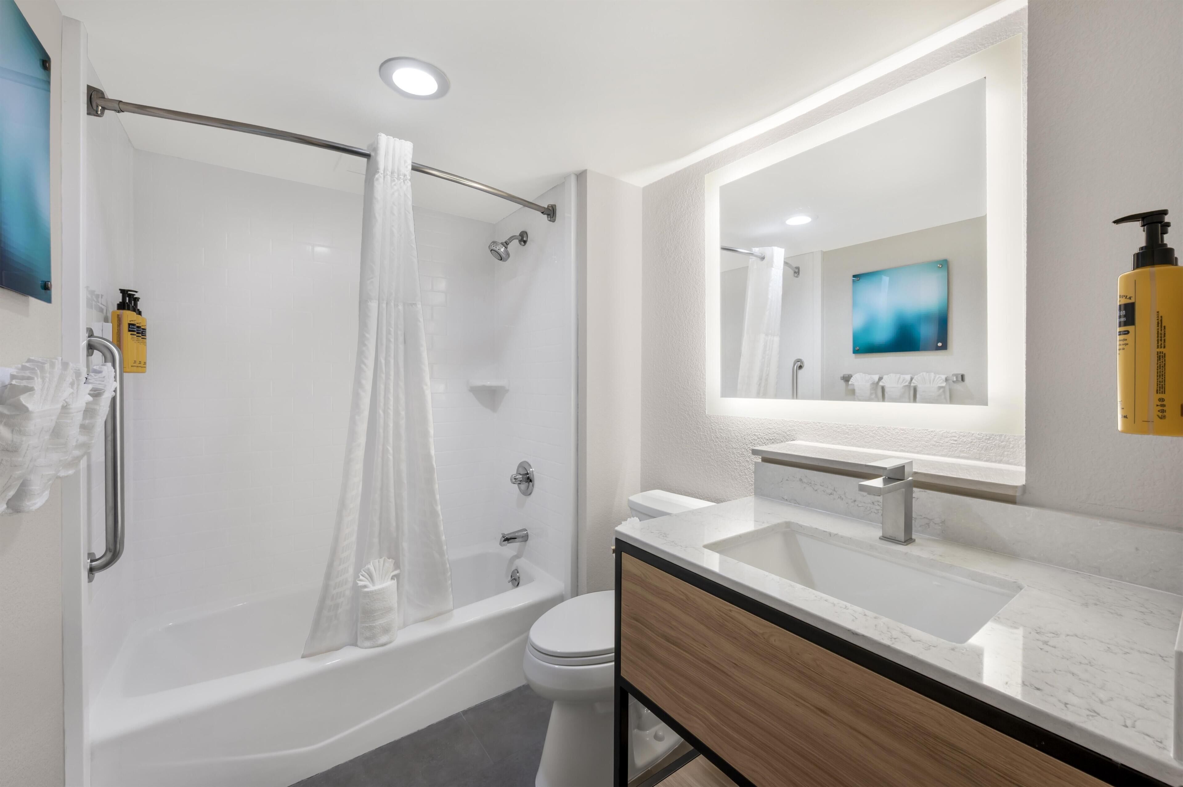 Une salle de bain moderne équipée d’une baignoire, de toilettes et d’un meuble-lavabo.