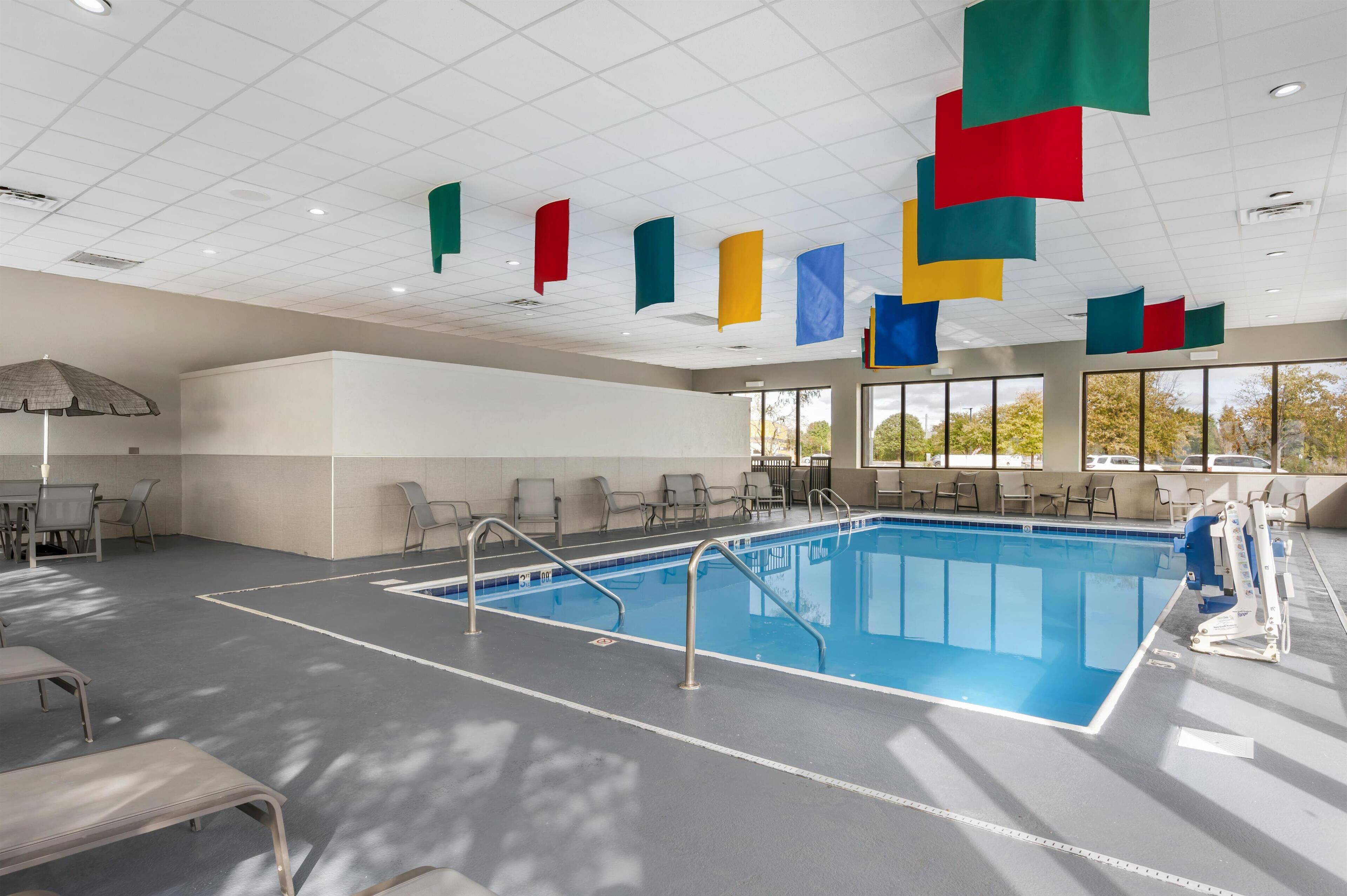 Ein Swimmingpool mit blauem Innenraum, umgeben von Stühlen und einem Sonnenschirm.