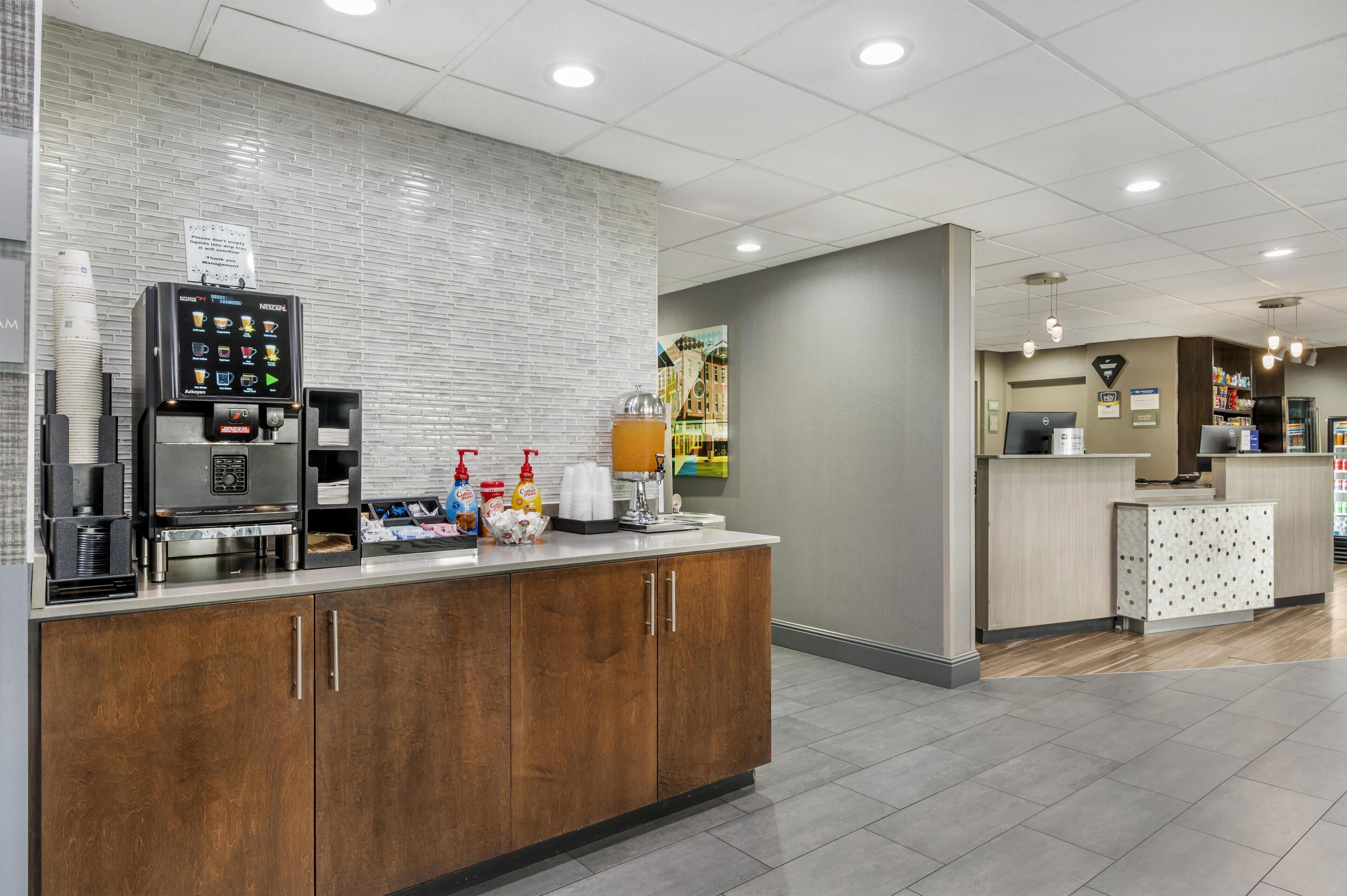 Eine moderne Hotelhalle mit einer Kaffeestation, einer Rezeption und einer Sitzecke.