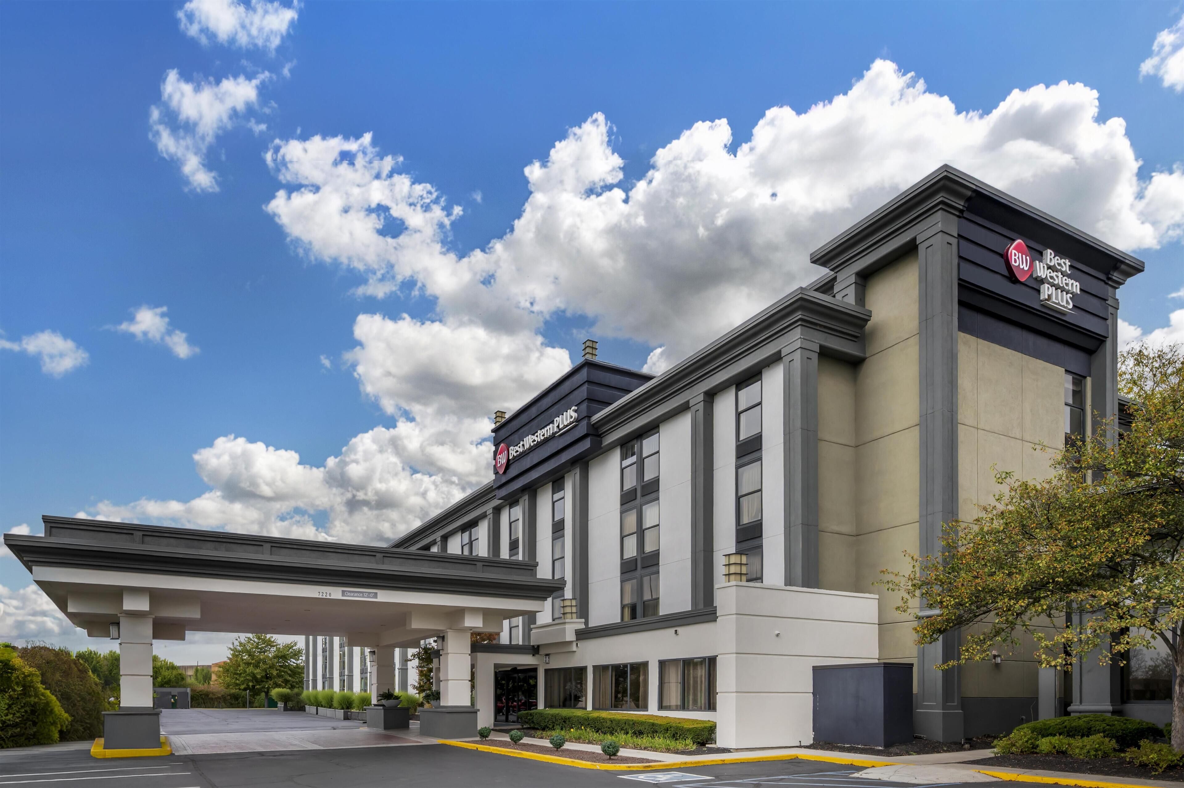 A hotel with a modern facade, a covered entrance, and a clear sky with clouds.