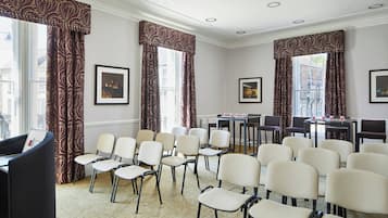 Un salón de conferencias con filas de sillas, un atril y cuadros en las paredes.