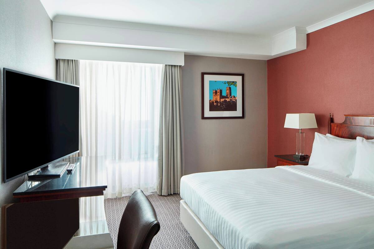 Una habitación de hotel con cama, televisión, escritorio y silla.