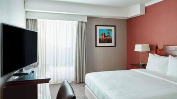 A hotel room with a bed, a TV, a desk, and a chair.