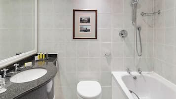 A modern bathroom with a granite sink, white toilet, and a bathtub.