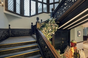 A grand staircase with ornate railings and a floral arrangement, leading to a door.