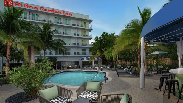 Un espace piscine avec des chaises longues et un panneau indiquant l’hôtel Hilton Garden Inn.