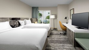Une chambre d’hôtel avec deux lits, un bureau doté d’un téléviseur à écran plat, une chaise et une vue sur l’extérieur.