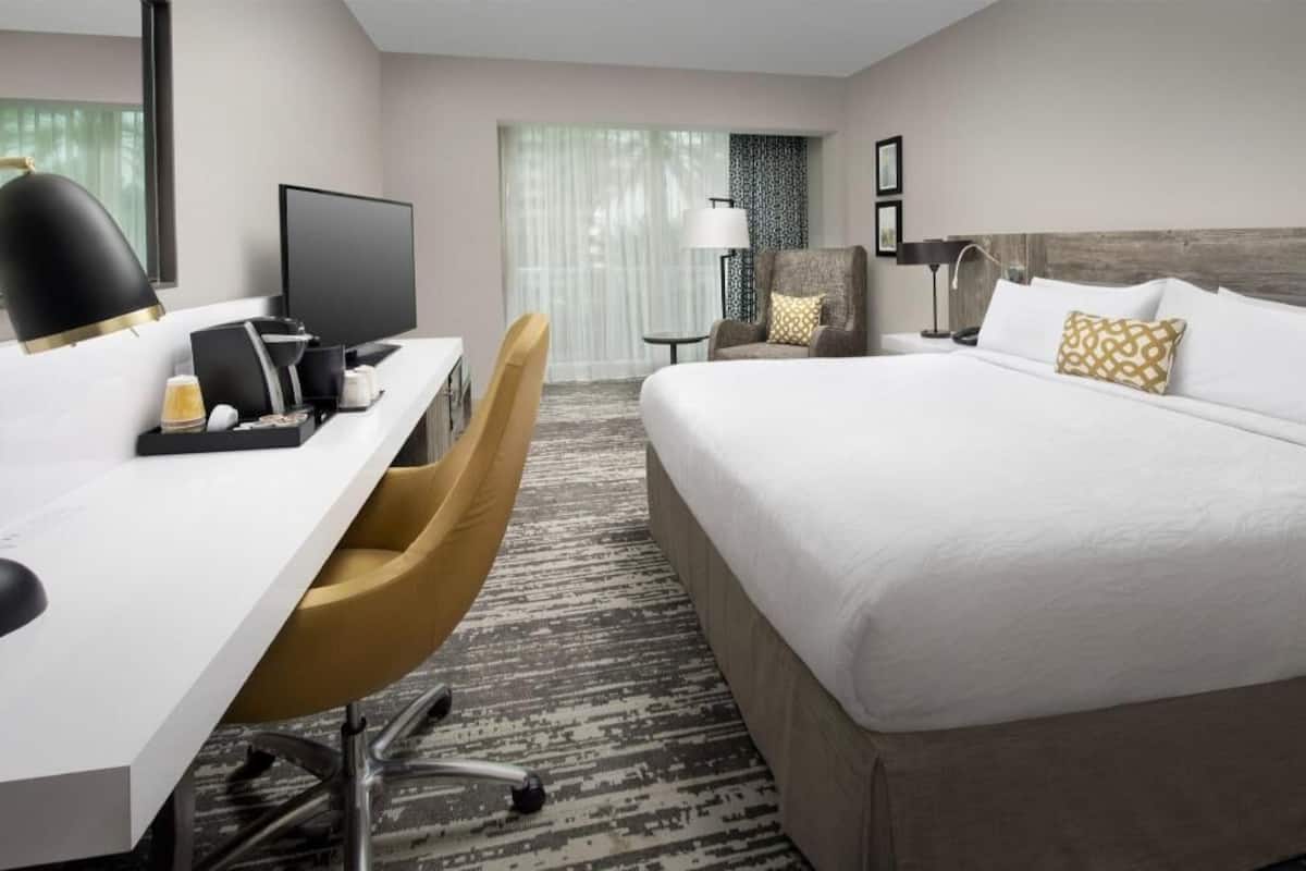 A hotel room with a bed, desk, chair, and a television.