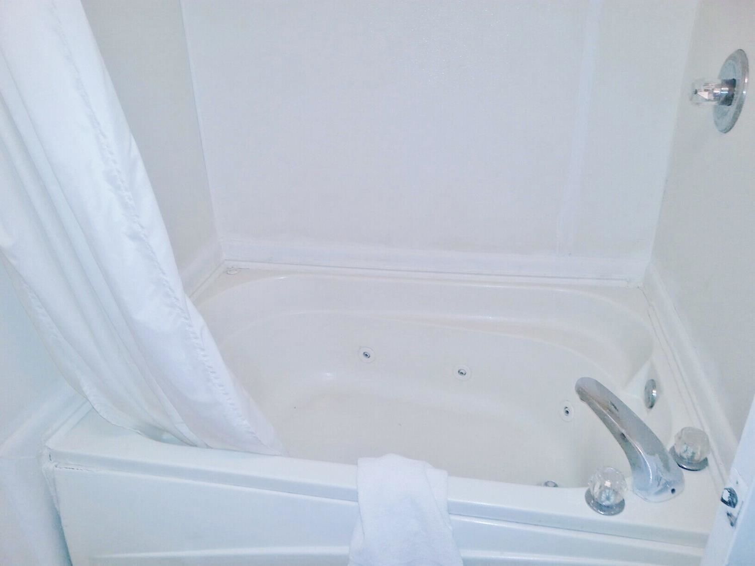 A white bathtub with a shower curtain, a towel hanging on the side, and a faucet.