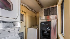 Eine kompakte Küchenzeile mit einer Maytag Gewerbewaschmaschine, einem kompakten Kühlschrank und einem Eiswürfelspender.