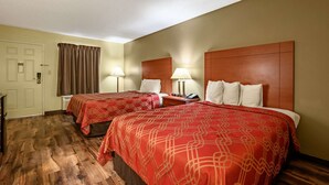 Ein Hotelzimmer mit zwei Betten, Holzkopfteilen und einer Tür mit Vorhang.