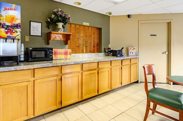 Kitchenette area with microwave, coffee maker, and shelf with flowers.
