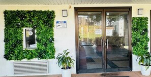 A building entrance with a glass door, a notice sign, and a security camera. - Econo Lodge Union City - Atlanta South (Union City)