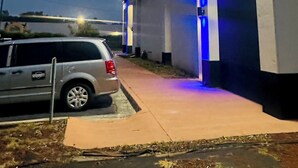 Un edificio con una puerta de garaje, una camioneta SUV estacionada y una acera.