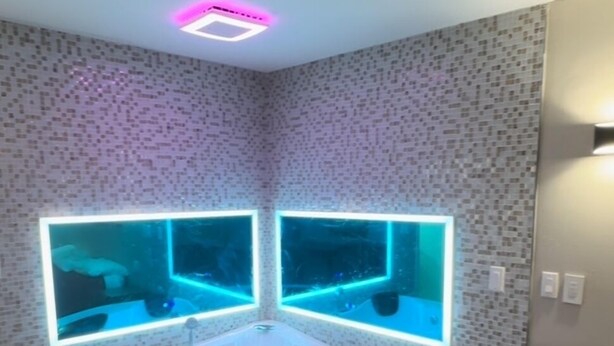 Un baño moderno con una bañera independiente, dos acuarios iluminados y un revestimiento de pared con diseño.