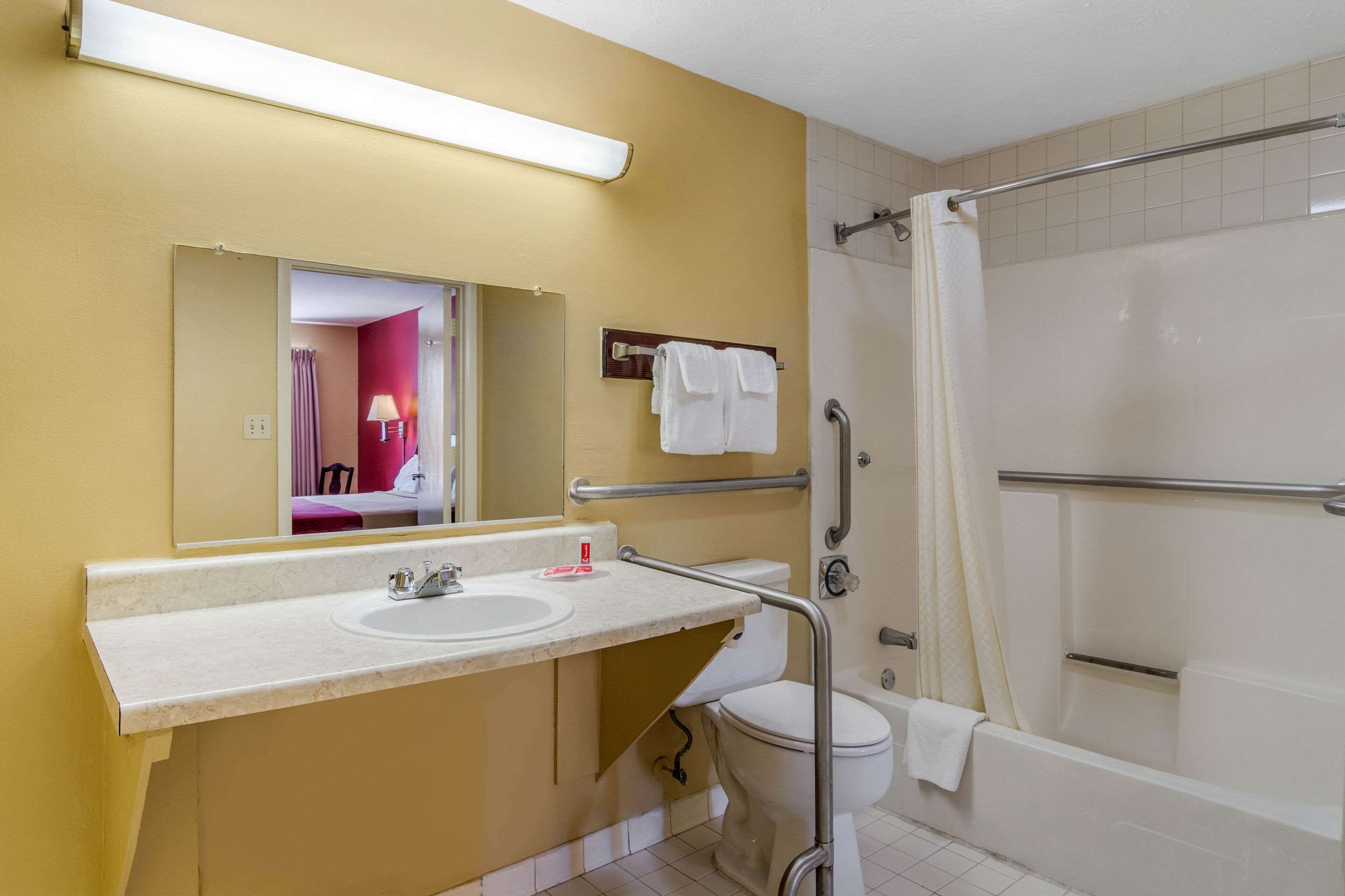 A bathroom with a sink, mirror, toilet, and bathtub.