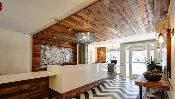 A reception area with a wooden ceiling, a modern reception desk, and a patterned floor. - The Inn at Venice Beach (Venice)