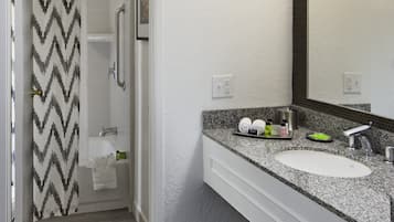 A bathroom with a shower, a sink, a mirror, and a vanity.
