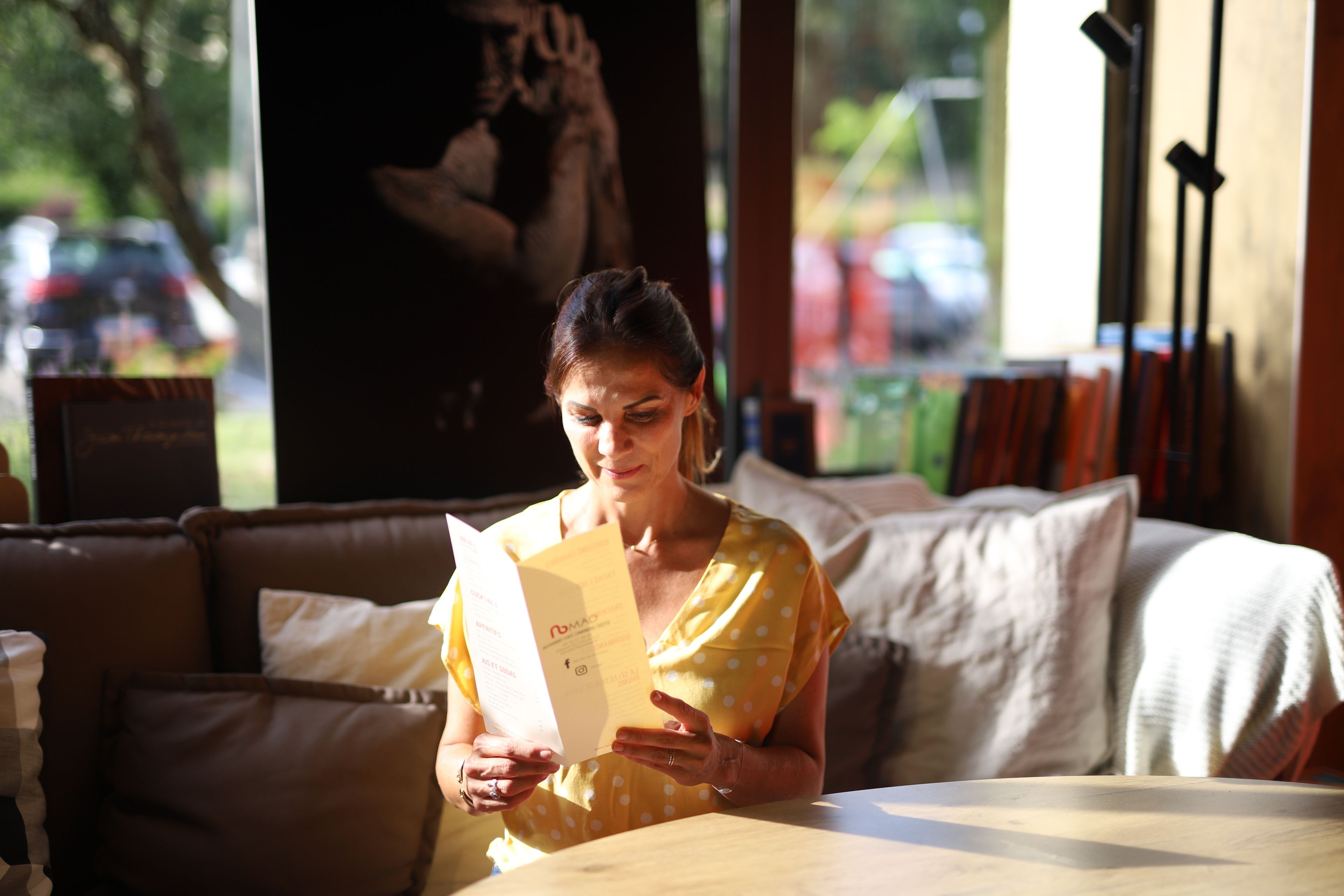 A person reading a book in a cozy room with a couch and a table.