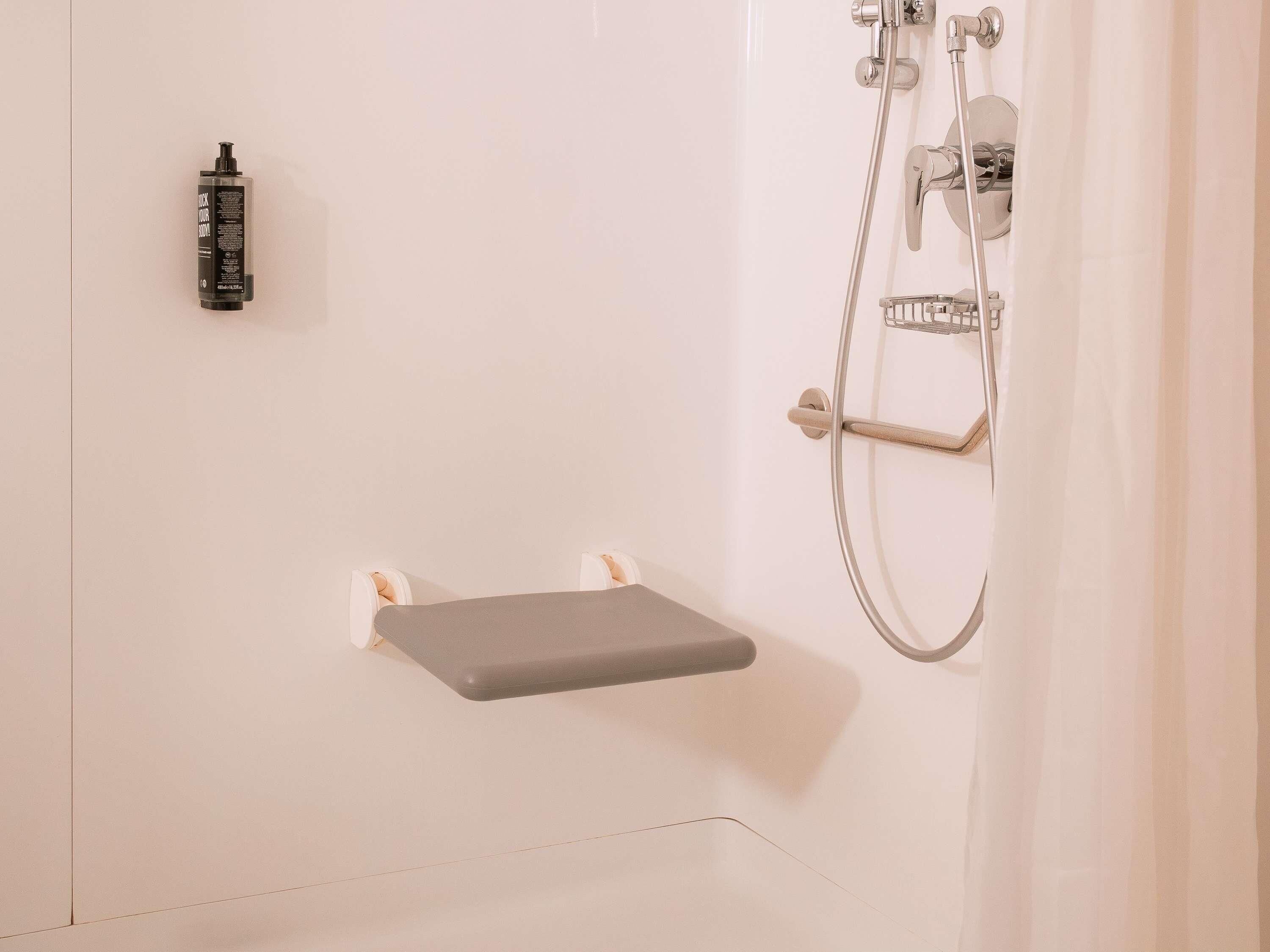 A shower with a handheld showerhead, a handheld shower attachment, and a soap dispenser.