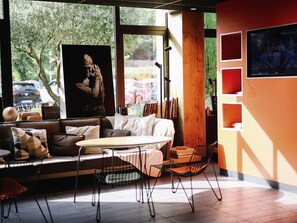 A modern interior with a sofa, a coffee table, and a bookshelf. - Ibis Aix en Provence Hotel (Aix-en-Provence)