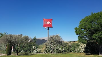 Un letrero rojo con la palabra 'ibis' en un día despejado.