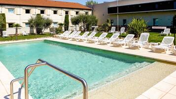 Una piscina al aire libre, sillones reclinables de piscina