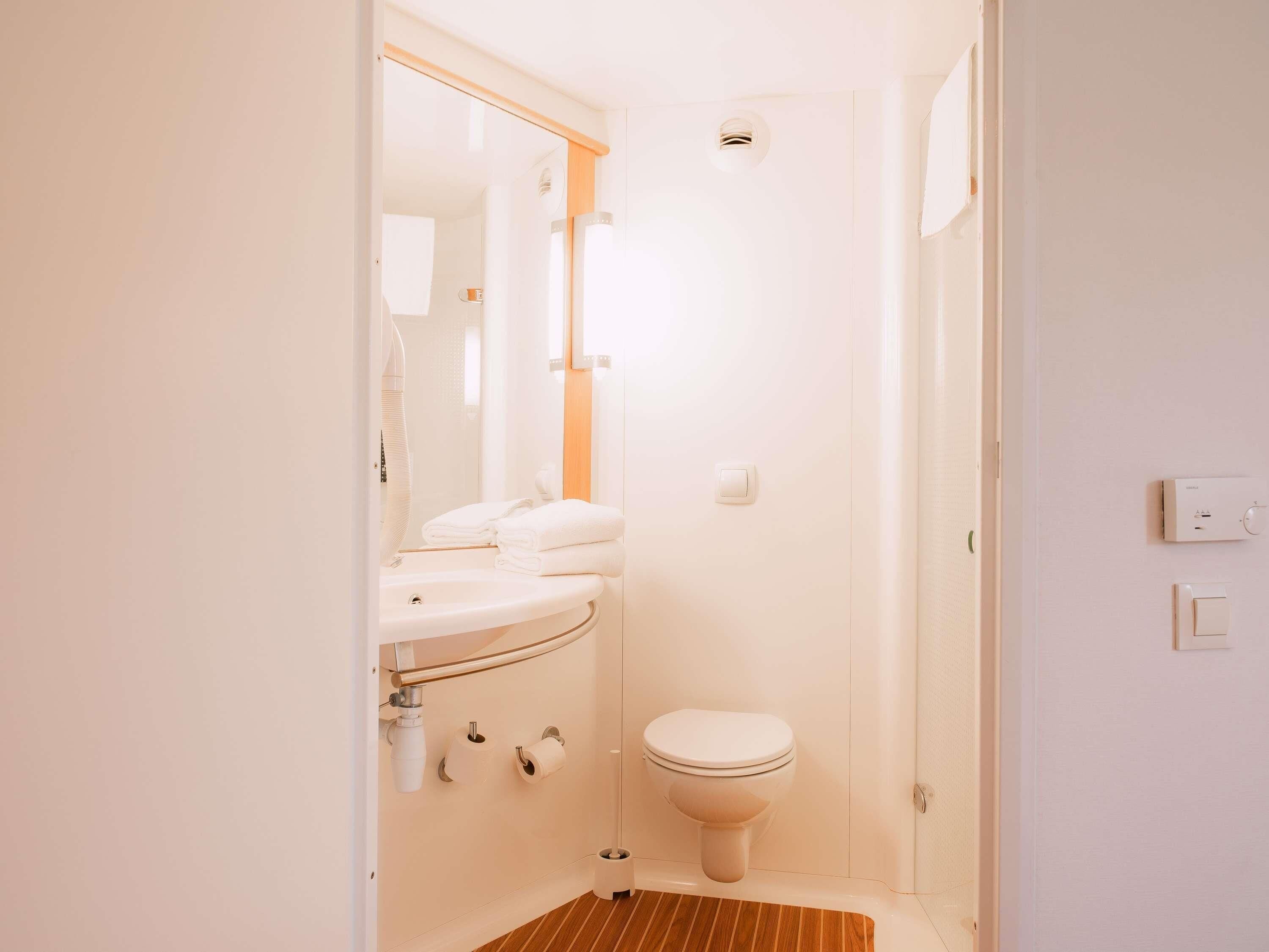 A compact bathroom with a toilet, sink, and mirror.
