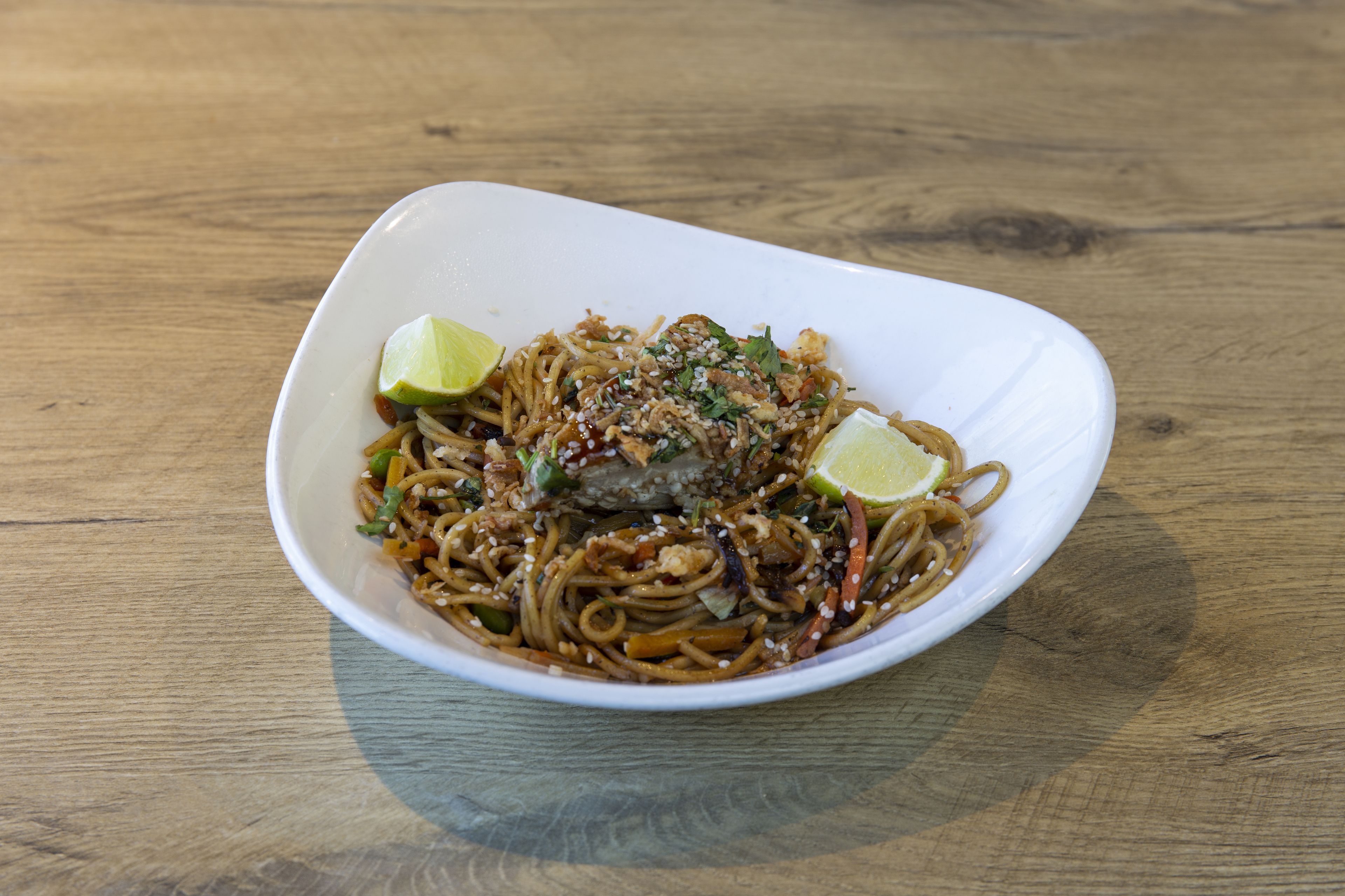 Un tazón de fideos sobre una mesa de madera.