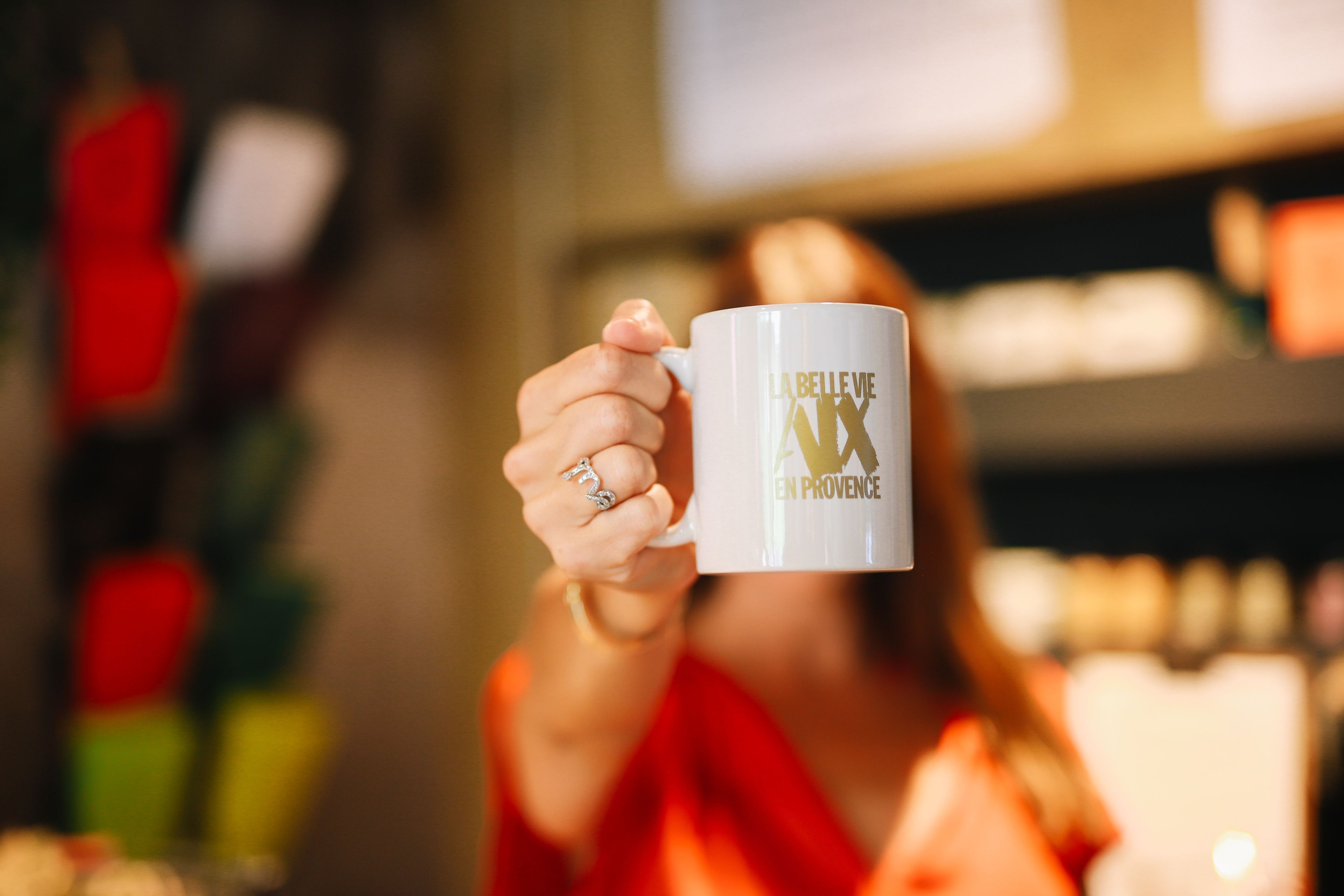 A person holding a white mug with text on it.