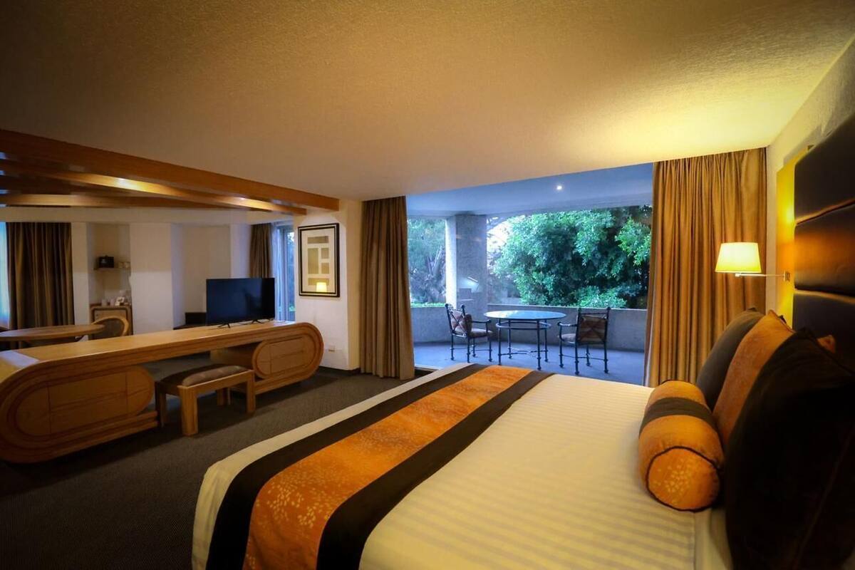 Une chambre d’hôtel équipée d’un lit, d’un bureau, d’une télévision et d’un balcon avec une table et des chaises.