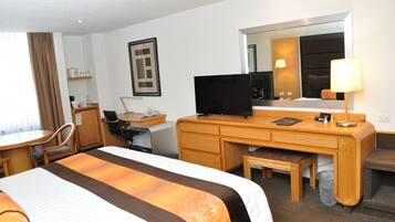 A hotel room with a bed, desk, chair, television, and a mirror.