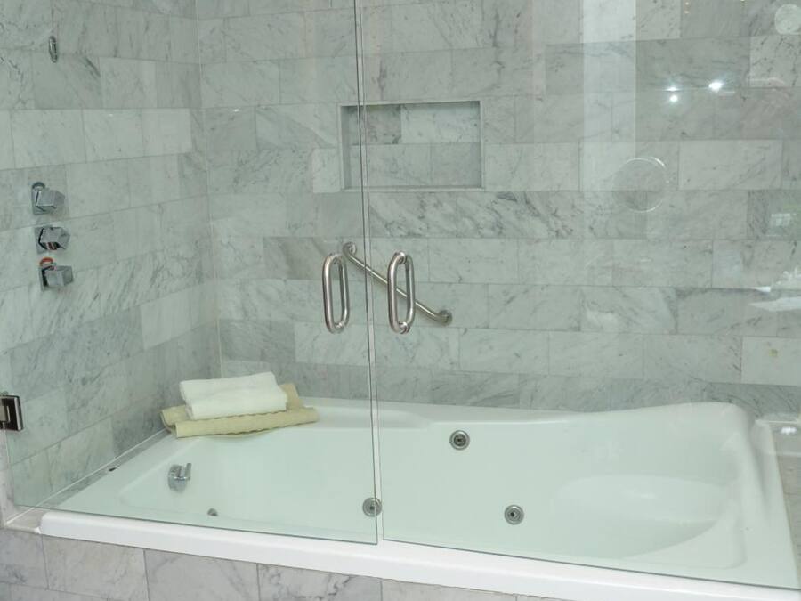 Uma casa de banho moderna com cabine de duche em vidro, uma banheira branca e sanita.