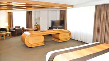Quarto de hotel com uma cama grande, uma secretária de madeira com uma televisão de tela plana, um sofá e uma mesinha.